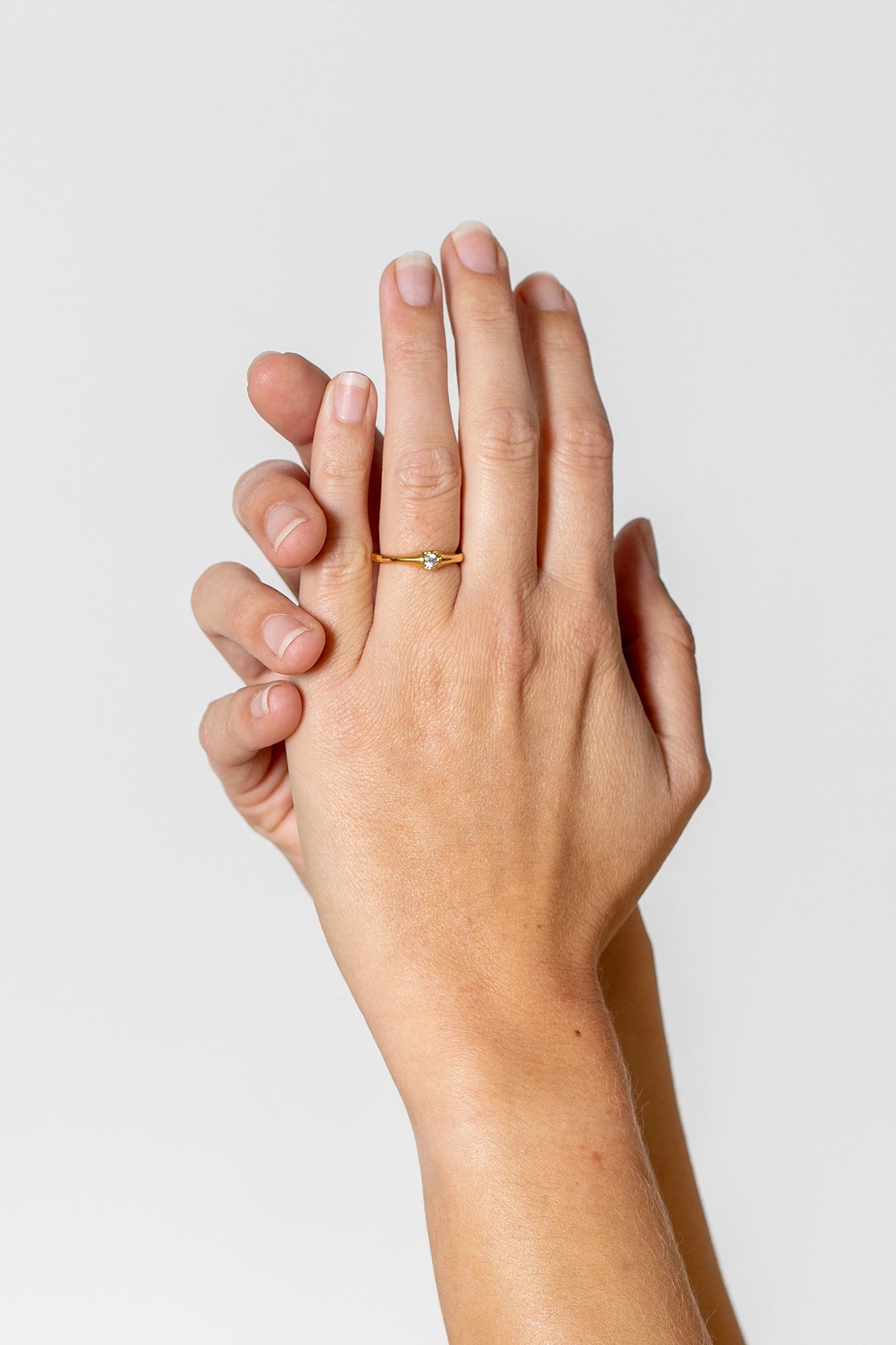 Tragefoto: zwei Hände mit einem goldenen Ring mit einem Brillianten